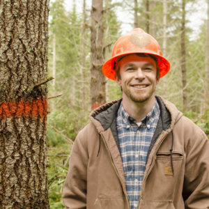 Man posing with a hard hat in front of a tree
