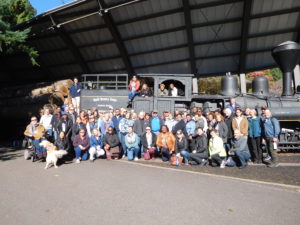 Large group of people posing in front of a logging train