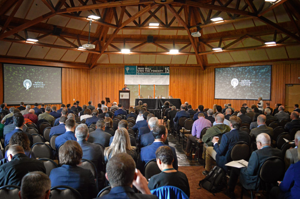 Large group of people listen to a lecture speaker and watch a presentation