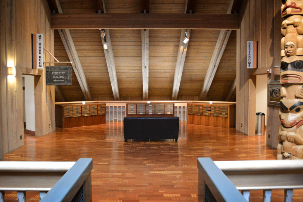 Room with wooden floors, walls, beams, chests of drawers and carved totem pole