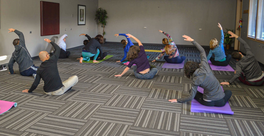 Group of people practicing yoga in a conference room